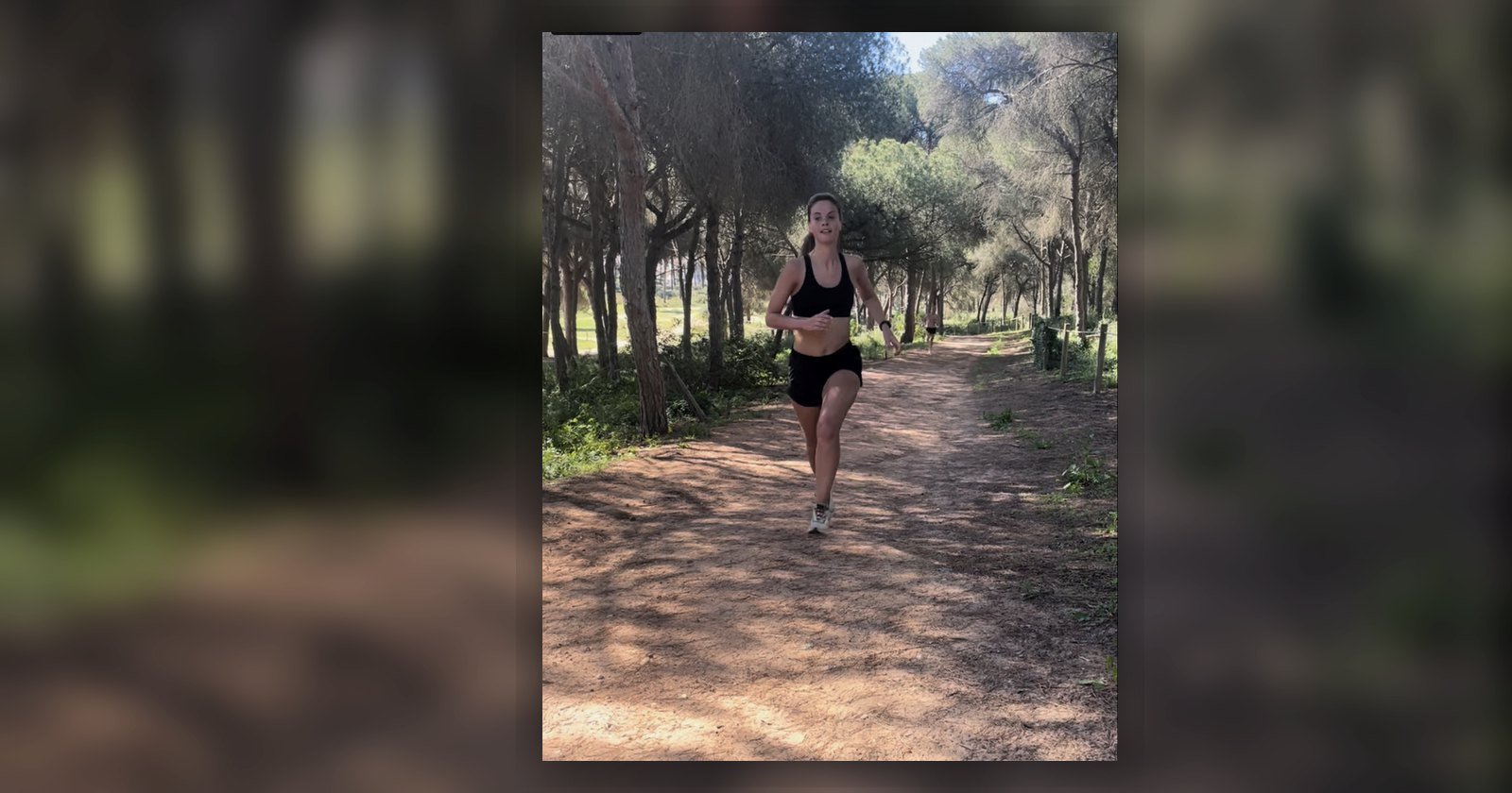 Runner driving uphill on a wooded trail, representing hill repeats and uphill sprint training